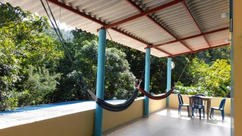 a porch with two hammocks and a table and chairs at EcoHostal Tierra Prometida in Santa Marta