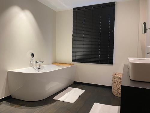 a white bathroom with a tub and a sink at Guesthouse next Do in Bruges