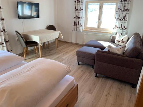 a living room with a couch and a table and a chair at Ferienwohnungen Hörmann in Hirschegg