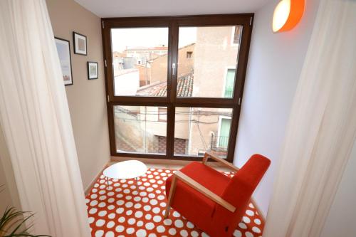a red chair sitting in front of a window at La Casa de las Aldeas in Daroca