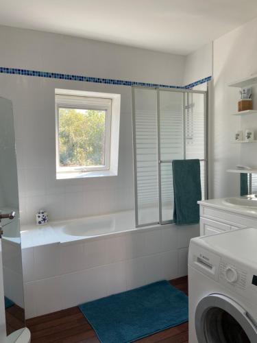 La salle de bains blanche est pourvue d'une baignoire et d'un lave-linge. dans l'établissement Appartement Douarnenez, Finistère sud, à Douarnenez
