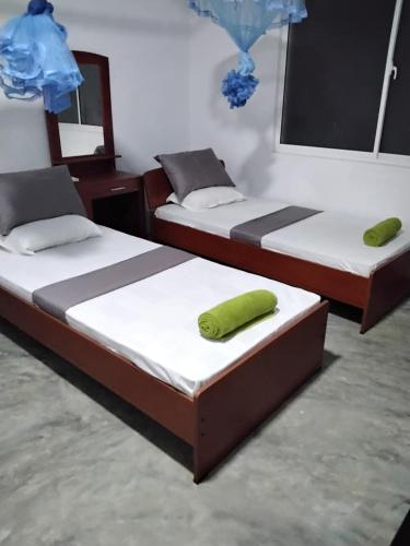 Duas camas num quarto com uma almofada verde em The Esence of Sri Lanka em Ahungalla