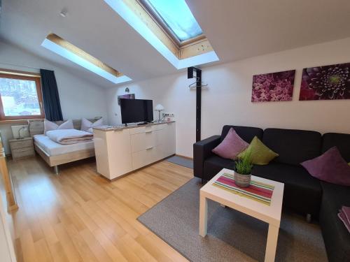 a living room with a black couch and a tv at Ferienwohnung Greber Gertraud in Bezau