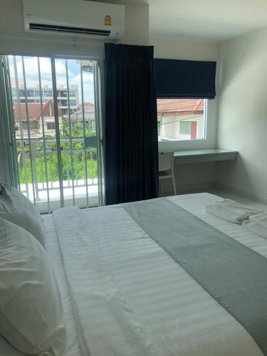 a bedroom with a large white bed and a window at Icare Residence & Hotel in Bangkok