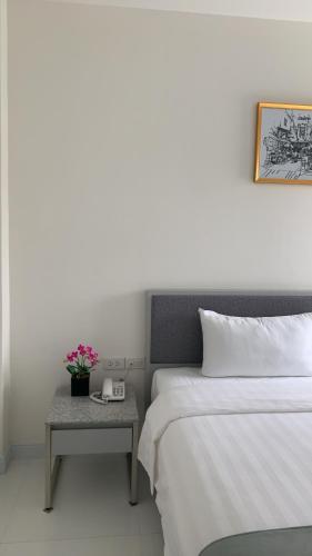 a bedroom with a bed and a table with a phone at Icare Residence & Hotel in Bangkok