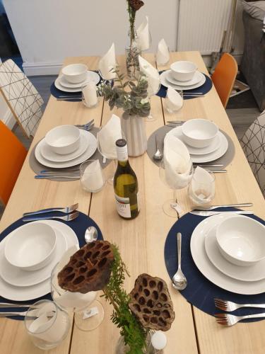 a long wooden table with white plates and a bottle of wine at Stunning 5 bed house, 2 mins to beach and town, with free parking in Blackpool