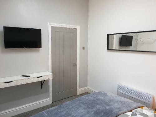 a white room with a bed and a television on the wall at Stunning 5 bed house, 2 mins to beach and town, with free parking in Blackpool