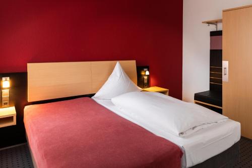 a bedroom with a large bed with a red wall at Tiemanns Boardinghouse in Lemförde