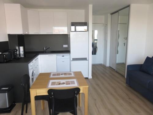 Il comprend une cuisine et un salon avec une table et un canapé bleu. dans l'établissement ANGLET-BIARRITZ Studio vue Mer - Terrasse + Garage, à Anglet