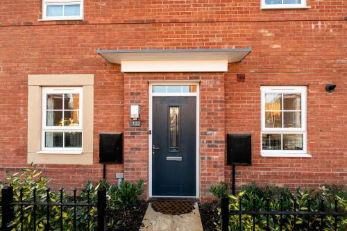 a red brick house with a black door at Fairfields Gem by by PAY AS U STAY in Milton Keynes