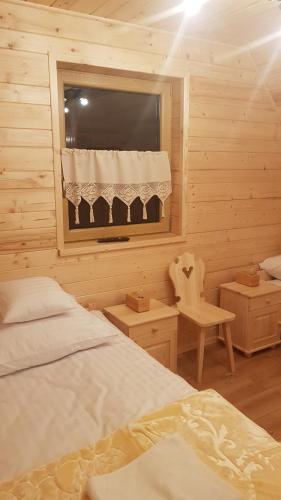 a bedroom with two beds and a window and a chair at Domek Przekolec in Szaflary