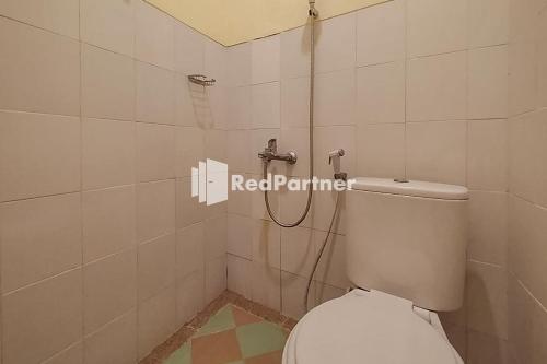 een badkamer met een wit toilet en een douche bij Batu Homestay Puncak Mitra RedDoorz in Pasirmuncang 1