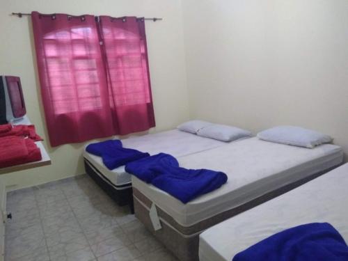 2 camas individuales en una habitación con ventana roja en Santo Ivo 3 en Aparecida