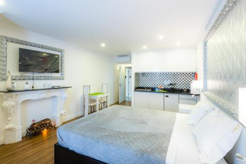 a white bedroom with a bed and a kitchen at Le Vingale in Funchal