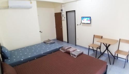 a room with a bed and a table and a television at รสริน ซีวิว in North Pattaya