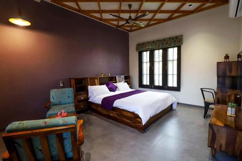 a bedroom with a large bed and a chair at Desert Palms by StayVista in Kutch, nestled in orchards, features a swimming pool and a scenic balcony for a serene getaway in Shinaya