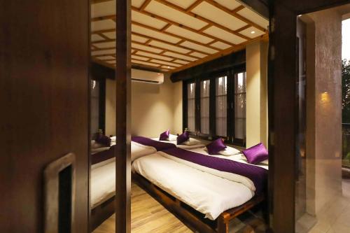 a room with three bunk beds with purple pillows at Desert Palms by StayVista in Kutch, nestled in orchards, features a swimming pool and a scenic balcony for a serene getaway in Shinaya