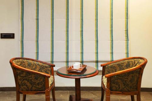 two chairs and a table with a plate on it at Desert Palms by StayVista in Kutch, nestled in orchards, features a swimming pool and a scenic balcony for a serene getaway in Shinaya