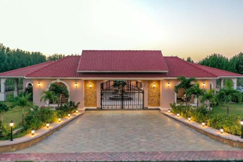a house with a gate and a driveway at Desert Palms by StayVista in Kutch, nestled in orchards, features a swimming pool and a scenic balcony for a serene getaway in Shinaya