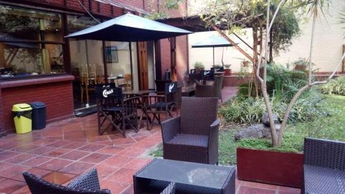 un patio con sillas, mesas y una sombrilla en Departamento de Gaby en Retiro en Buenos Aires