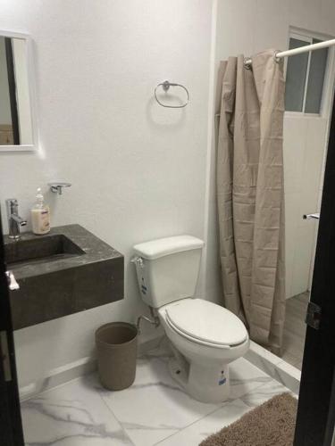 a white bathroom with a toilet and a sink at Departamento en Acapulco Diamante in Acapulco