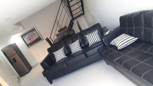 a living room with a black leather couch with pillows at APARTAMENTO ZONA COLONIAL in Santo Domingo