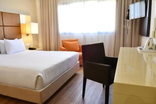 a hotel room with a bed and a chair at Holiday Inn Madrid - Las Tablas by IHG in Madrid