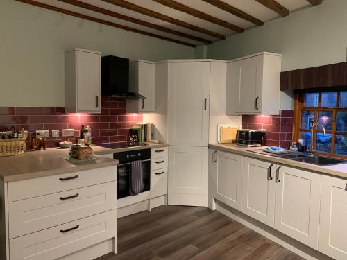 eine weiße Küche mit weißen Schränken und einem Fenster in der Unterkunft Apartment One, The Carriage House, York in York