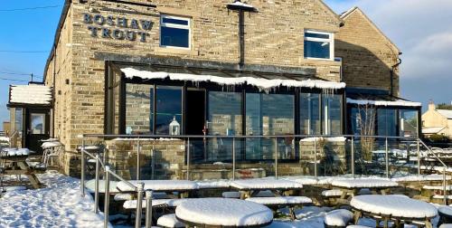 a building with snowcovered tables and chairs in front of it at The Boshaw Trout in Holmfirth