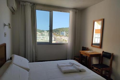 sypialnia z łóżkiem, biurkiem i oknem w obiekcie Hotel Escorial w mieście Piriápolis