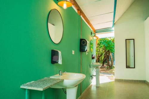 a green bathroom with a sink and a mirror at Selina River Venao in Playa Venao