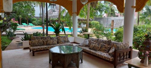 a patio with couches and a table and a pool at The Villa Mela, Malindi in Malindi