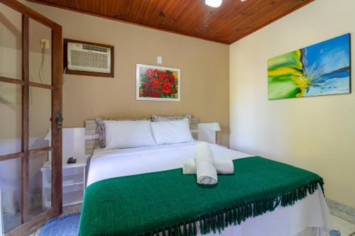 a bedroom with a bed with a green blanket at Pousada Recanto da Terra, fácil acesso a Rua Mucugê e Beco das Cores in Arraial d'Ajuda