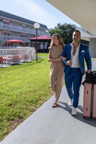 a man and a woman walking down a sidewalk with luggage at Equus Inn I75 in Ocala