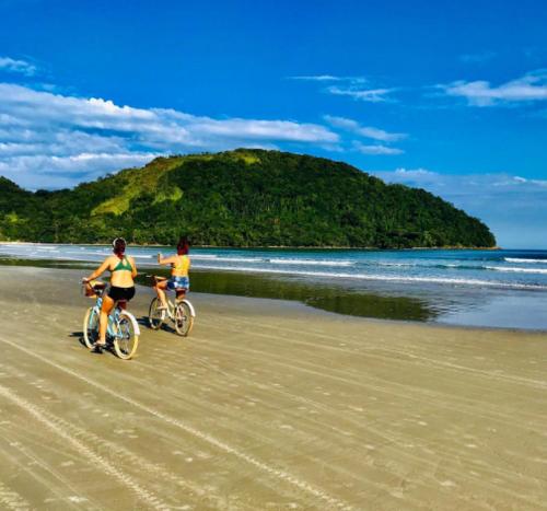 zwei Personen, die am Strand Fahrrad fahren in der Unterkunft Ganesh Chalés in Boracéia