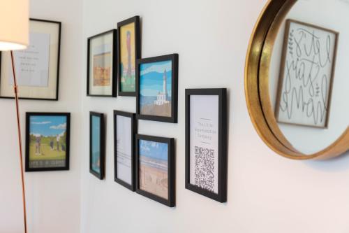 a wall of framed pictures on a wall with a mirror at Turnberry accommodation in Turnberry