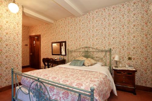 a bedroom with a bed in a room with wallpaper at Hodgkinsons Hotel & Restaurant in Matlock