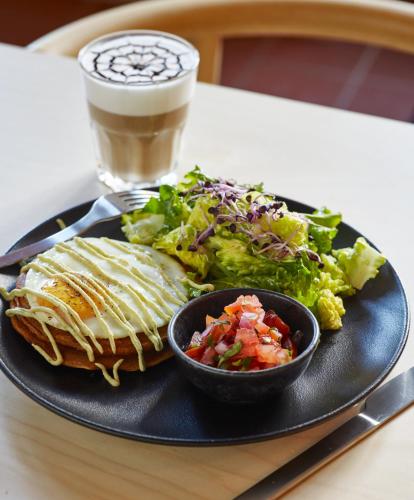 a black plate with a sandwich and salad and a drink at Cosmiques Hotel - Centre Chamonix in Chamonix-Mont-Blanc