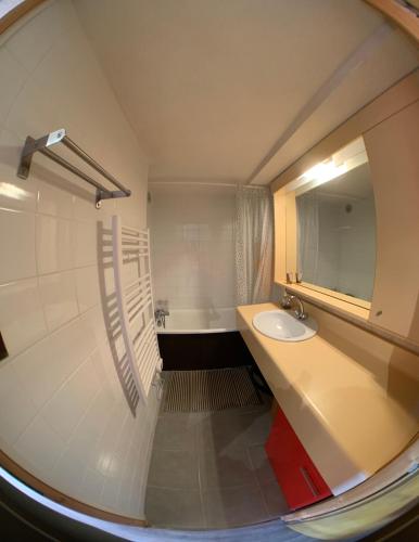 een badkamer met een wastafel, een spiegel en een bad bij Location appartement Chamrousse 1650 - Superbe vue in Chamrousse