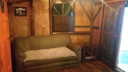 a brown couch in a room with a window at Hostal ComplejoTurístico Santa Isabel in Iza