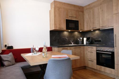 kuchnia z drewnianym stołem i czerwoną kanapą w obiekcie Bergliebe Apartments w mieście Gerlosberg