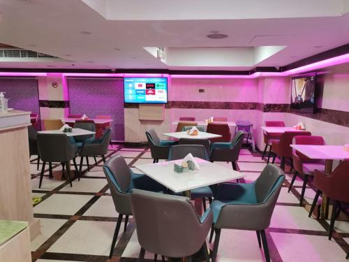 un restaurante con mesas, sillas y paredes rosas en Saffron Hotel, en Dubái