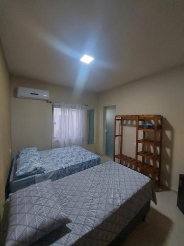 a bedroom with two beds and a book shelf at Suites Pouso Familiar José e Maria in Paraty