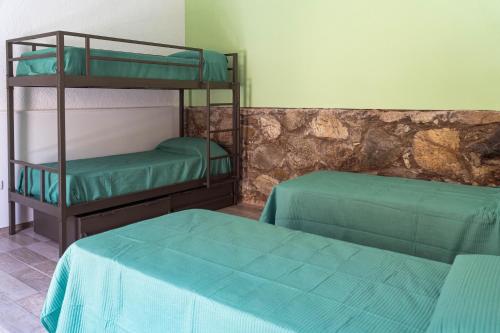 two bunk beds in a room with green sheets at Nomades Hostel in Alta Gracia