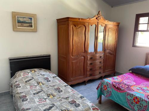 a bedroom with a wooden cabinet and a bed at Vila Colorida casa 2 in Fazendinha