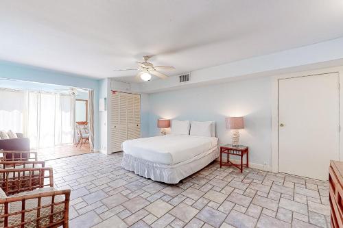a bedroom with a white bed and a table and chairs at Landfall Tower Unit 43 in South Padre Island