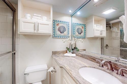 a bathroom with a sink and a toilet and a mirror at Landfall Tower Unit 43 in South Padre Island