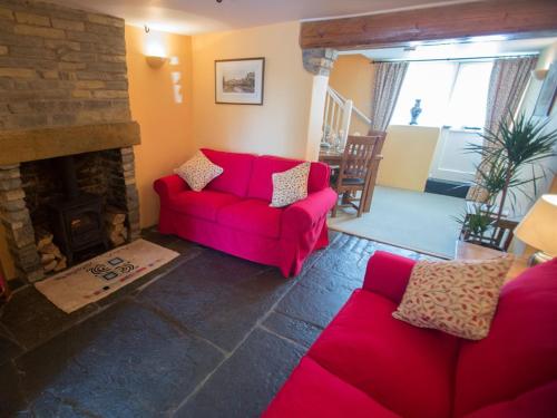 a living room with a red couch and a fireplace at Withy Cottages in Langport