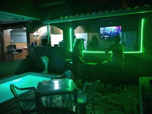 um grupo de pessoas sentadas num bar com piscina em Pousada casa nostra em Piúma