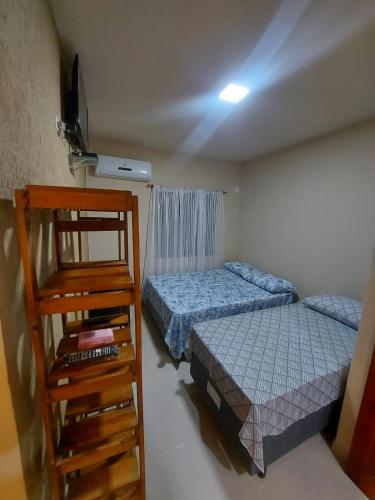 a bedroom with two beds and a television in it at Suites Pouso Familiar José e Maria in Paraty